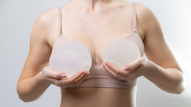 Female adult caucasian holding silicone breast implants in hands