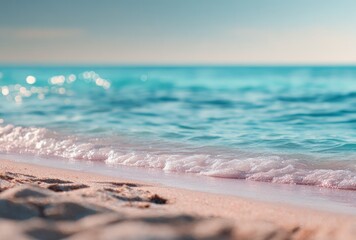 Gentle waves caress the sun-kissed shore, blurring the horizon where the blue sea meets the sky on a bright, sunny day, sandy footprints below
