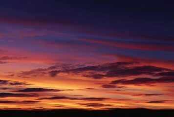 A vibrant sunset showcases fiery orange blending into deep purple hues across the sky, with dark silhouettes grounding the colourful panorama