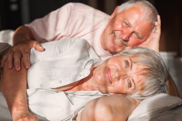 Happy elderly couple wakes up in bed in the morning