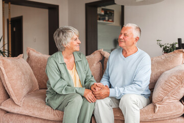 Portrait of a beautiful senior couple embracing each other, sitting on the couch at home