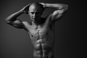 Fototapeta premium Black and white image of a muscular man posing confidently, showcasing strength and determination with a striking expression, ideal for fitness inspiration.