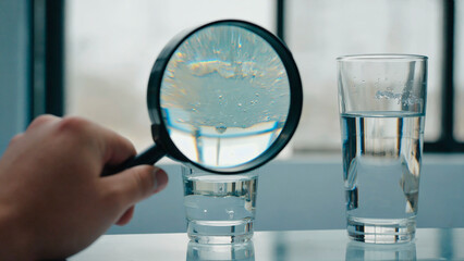 Magnifying glass examining glass of water.