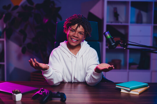 Cheerful man vlogger with microphone sharing thoughts in neon lit room showing modern online interactive media