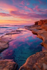 Coastal rock pool reflecting a vibrant sunrise