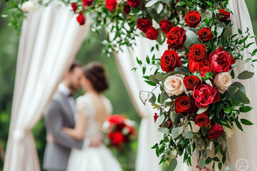 Romantic wedding with red roses adorning a charming floral archway ceremony
