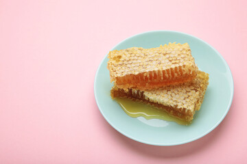 Sweet honey combs on mint plate on pink background
