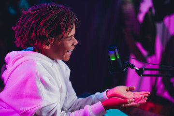 Funny teen streamer podcasting with energy and charm in a neon-lit studio using professional equipment for online blogging