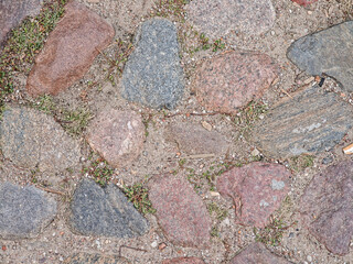 Old cobblestone pavement with natural stones and grass