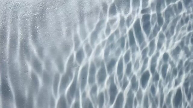 Hypnotic Ripples of Sunlight Refracting Through Water Creating Shimmering Caustic Patterns on a Surface.