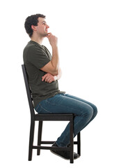 Side view casual guy seated on a chair keeps hand under chin thoughtful looking away, has a lot of plans and goals. Positive male full length portrait isolated on transparent background