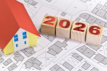 2026 HOUSING MARKET AND REAL ESTATE PLANNING CONCEPT - Business concept in building activity and construction industry - New financial year and Budget 2026 concept with home model and cadastral map