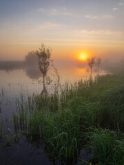 Scenic autumn view of beautiful sunrise in the morning time over river with mist