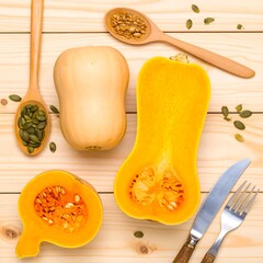Fresh butternut squash halves and whole, showcasing vibrant orange flesh and pale tan rind, arranged on a light-colored wooden surface with pumpkin seeds, with a rustic feel.
