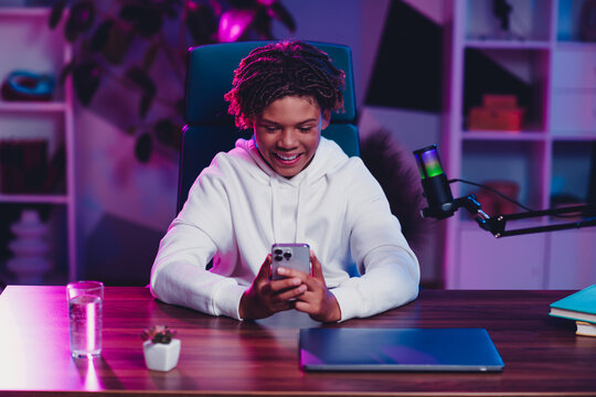 Teen boy creating engaging online content at a streaming desk with vibrant neon lighting in a modern home studio environment