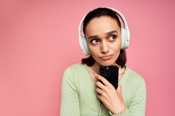 Brunette woman in stylish green cardigan enjoying music in a vibrant pink setting