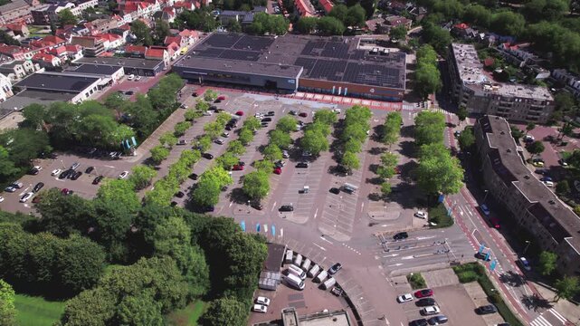 Shaky searching aerial of parking lot in front of large Dutch supermarket chain exterior facade in tower town Zutphen city center seen from above