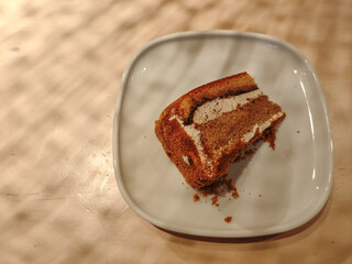 A delicious slice of mocha cake on a plate in a wooden table