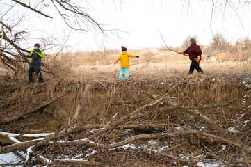 Exploring nature with playful adventures among sticks and branches in a serene countryside setting during a crisp winter afternoon