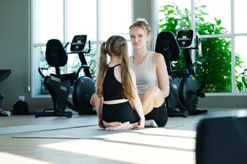 A young woman and a girl are exercising at the fitness center, reflecting the concept of fitness.