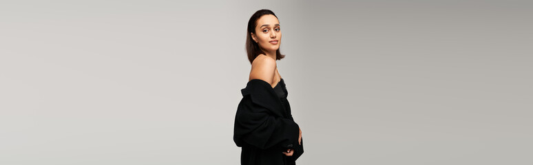 Stylish brunette model poses gracefully in chic black outfit in studio setting