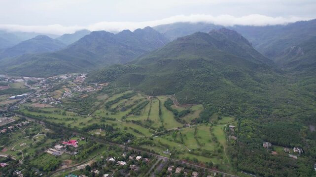 An aerial drone video of Islamabad's urban and natural beauty, featuring the city, Margalla Hills, and a green golf course.