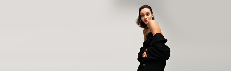 Brunette woman exudes modern elegance in a black outfit in a studio