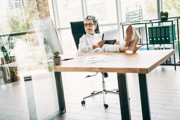 Confident businesswoman working in a modern office workspace while reviewing documents and...
