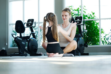 A young woman and a girl are exercising at the fitness center, reflecting the concept of fitness.