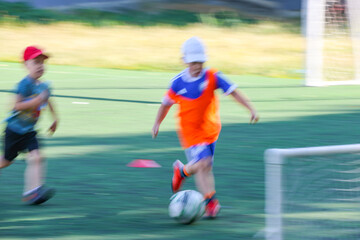 Obraz premium little boys plays football at a sports school .Blur.