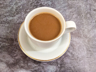 Authentic Indonesian Kopi Susu or instant coffee. Rich, creamy milk coffee in a classic ceramic white glass and saucer. 
