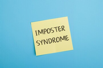 Sticky note on blue backdrop illustrating the idea of IMPOSTER SYNDROME, characterized by self-doubt about abilities and a hidden fear of being unmasked as a fraud