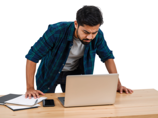 Young professional with a concerned expression working on a laptop at his desk