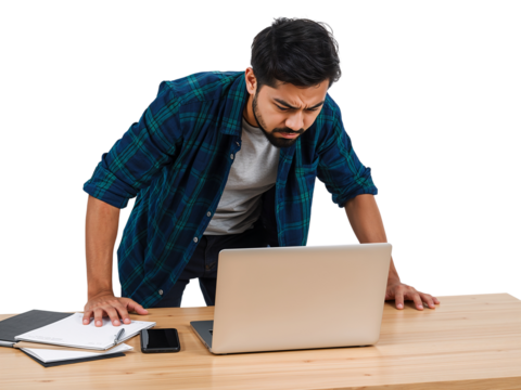 Young professional with a concerned expression working on a laptop at his desk