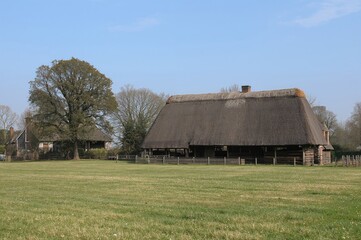 Obraz premium Thatched roof farmhouse and barn in a quiet rural region with expansive grass and trees