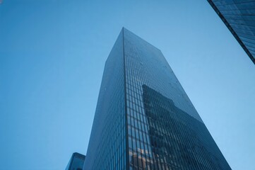 Fototapeta premium Double exposure of a towering glass structure with a panoramic wide-angle perspective against a steel blue backdrop, symbolizing modern commercial success in urban architecture.