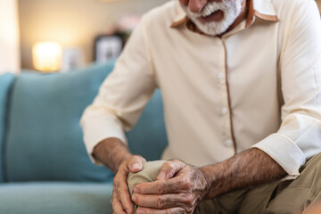 Senior man, knee pain and arthritis on couch with home, leg massage and joint problem with gout....