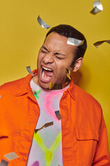 Vibrant Indian man showcases bold fashion in lively studio setting with confetti