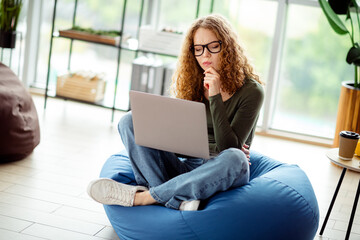 Young woman using a laptop for work or study in a cozy indoor setting