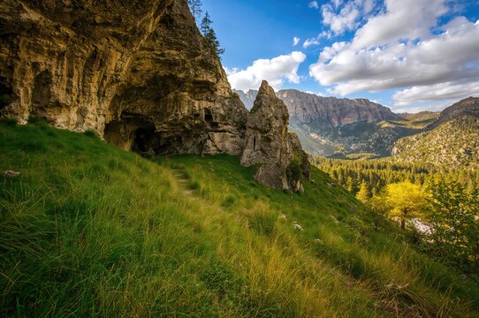 Exploring a rocky cave nestled in a lush mountainous landscape with greenery and natural stone formations