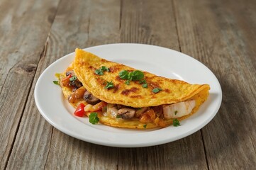 Vegetable and herb omelet cooked to golden perfection, presented on a white dish over a wooden surface