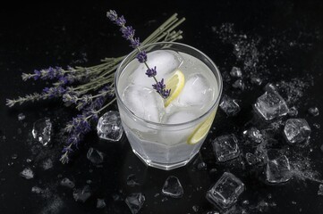 Summer detox beverage with lavender, lemon, and ice on a dark backdrop, ideal for a diet cocktail. Ample space for personalization.