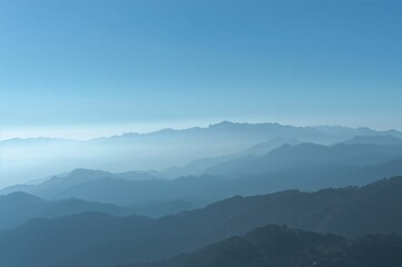 Naklejka premium Silhouetted peaks under a hazy azure sky on a sunny day, beautiful natural landscape in a European region
