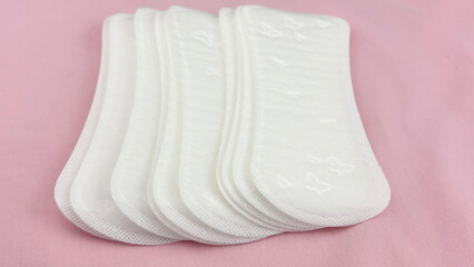 Women's sanitary pads on pink background, top view. Feminine hygiene and menstruation product. Daily pad for period care, women's health, advertising, article or banner concept