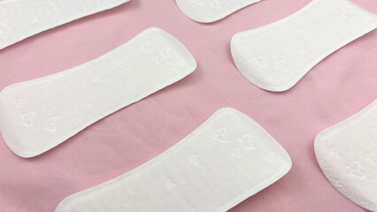 Women's sanitary pads on pink background, top view. Feminine hygiene and menstruation product. Daily pad for period care, women's health, advertising, article or banner concept, background