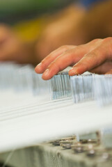 Industria textil, maos consertando os fios nos teares 