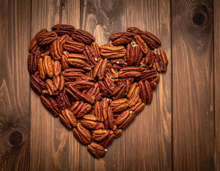 Pile of love shaped pecans on a wooden background.