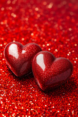 Obraz premium Two red hearts on a red glittery background
