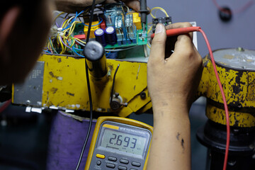 Close-up of Technician Using Digital Multimeter on Circuit Board