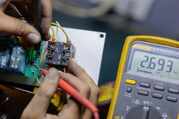 Close-up of Technician Using Digital Multimeter on Circuit Board